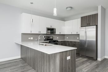 a kitchen with a large island and stainless steel refrigerator